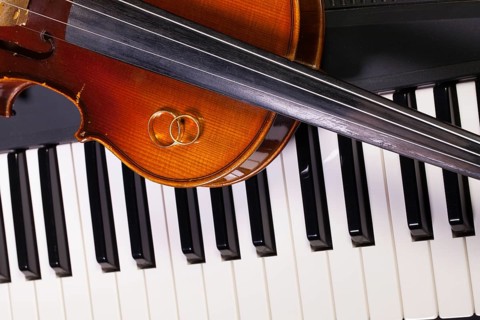 Detail of piano keyboard, old violin and wedding rings