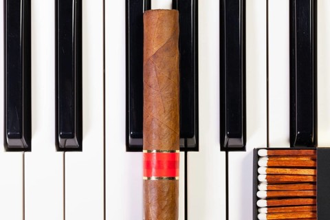 Detail of piano keyboard and luxury cigar
