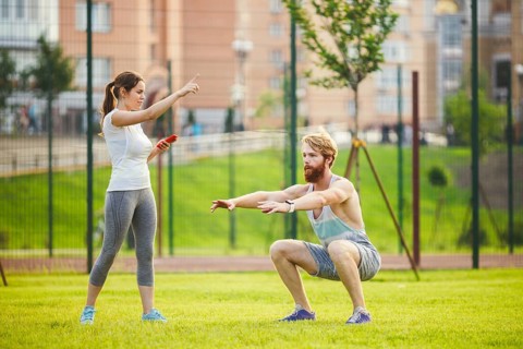 Team work in sports. female trainer training man with beard in park on green grass, lawn at sunset.