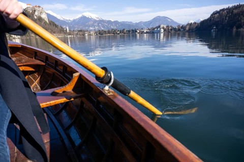 Young woman using paddle on a wooden boat, Lake Bled Slovenia rowing on wooden boats on a sunny day