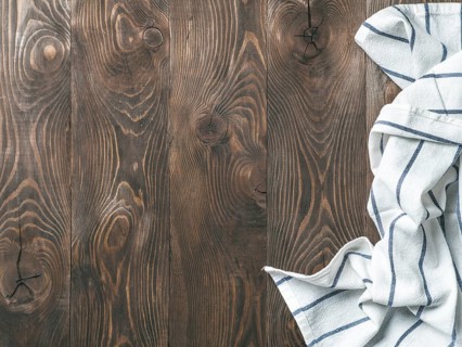 View from above on brown wooden table with linen kitchen towel or textile napkin. Blue tablecloth