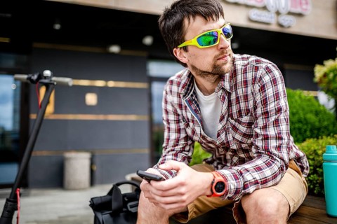 Individual urban environmental friendly transport electric kick scooter parked near man sitting on