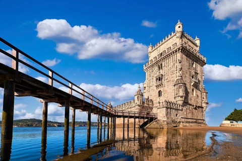 Belem tower and wooden bridge to it, Lisbon, Portugal at blue summer day sky with clouds. Medieval