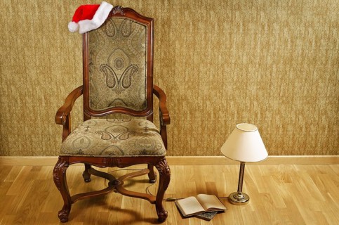 Old armchair with Santa hat and a lamp with a book near it