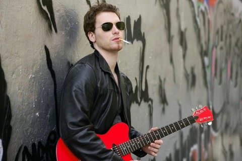 Smoking cigarette rock leather boy playing guitar outdoor on silver wall backgorund