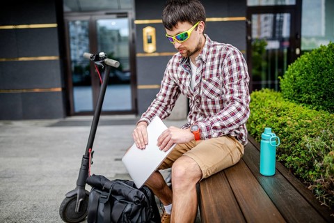 Young caucasian man in casual clothes freelancer uses eco-friendly electric transport scooter. Male