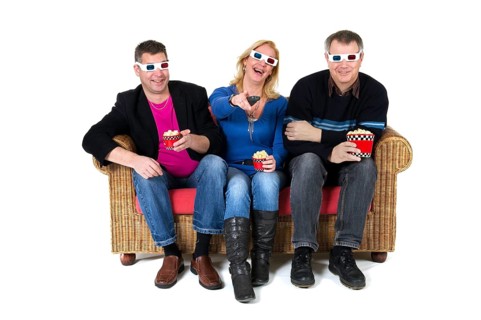 Three persons are laughing about the 3D movie on televison