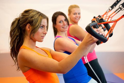 Young woman doing suspension training at the health club
