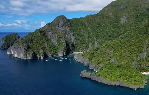 Aerial view of tropical Philippines island. White sand beach, rocks cliffs mountains with blue bay