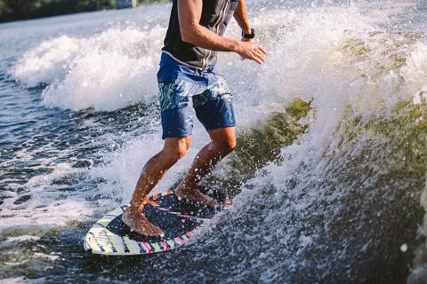 Active wakesurfer jumping on wake board down the river waves. Surfer on wave. Male athlete training