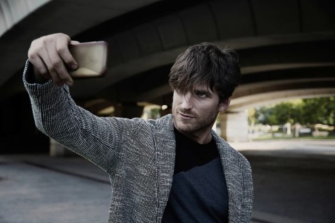 Modern young man smartphone taking selfie photos under a bridge