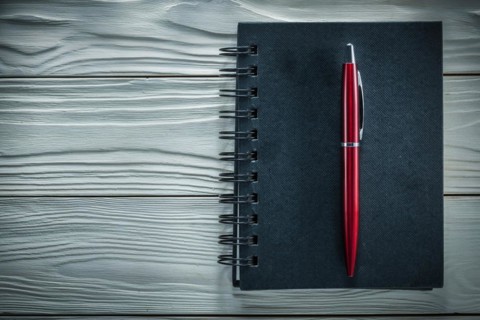 Black notepad pen on a white wooden board