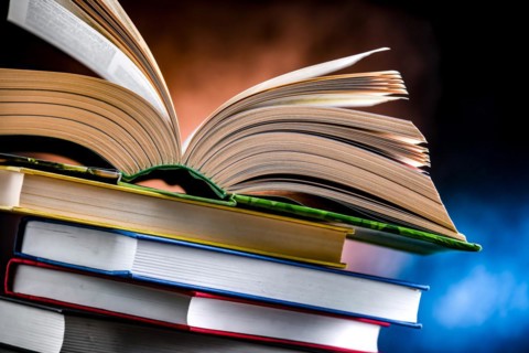 A composition with an open book lying on a stack of other books