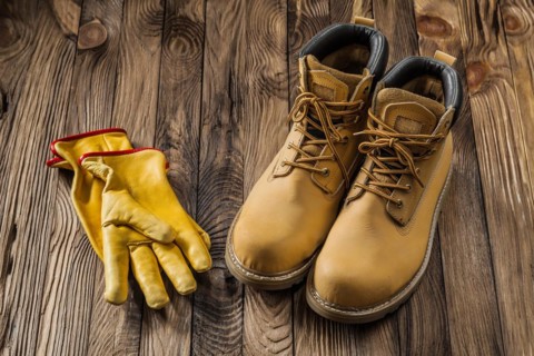 Construction safety tools yellow working gloves and leather working boots on vintage wooden