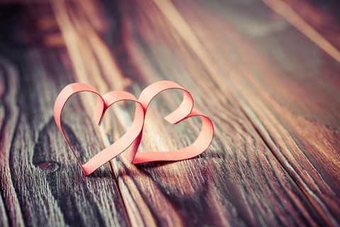 Two paper hearts on wooden background in vintage look - soft focus. Symbol of love. Space for text