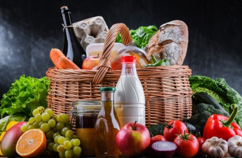 Wicker basket with assorted grocery products including fresh vegetables and fruits