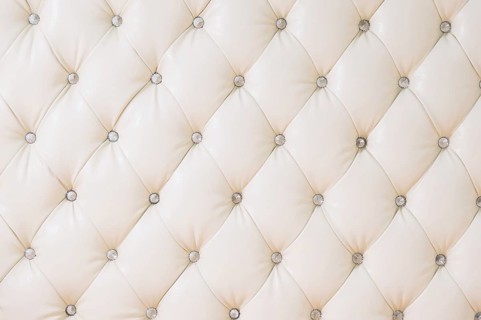 Beige soft tapestry pattern background with symmetrical buttons on the corners of diamonds. Soft