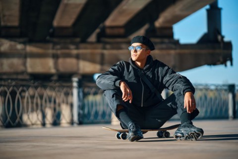 Skater male relax sitting on skateboard on street urban background. Extreme sports concept