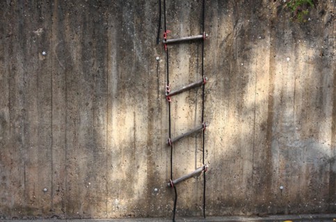 Rope ladder on a concrete wall with sunlight reflections