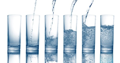 Pouring of fresh cool water in a glass isolated on white background