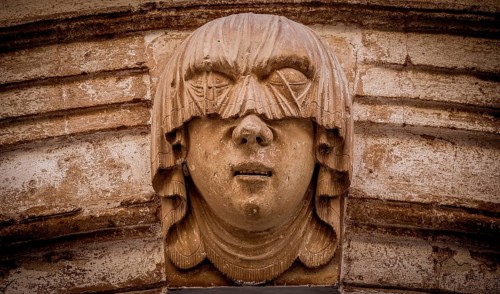 Gothic detail. Young woman portrait at the entrance of a 200 years old building in Ciutadella town,