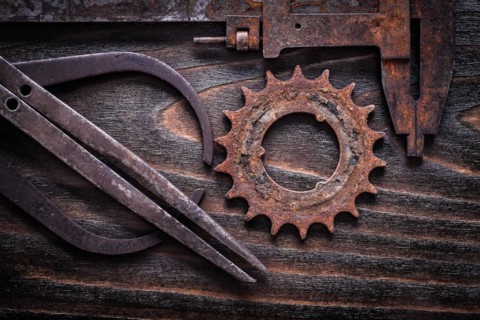 Rusted antique measuring calipers with cog- wheel on vintage dark wooden background close up view