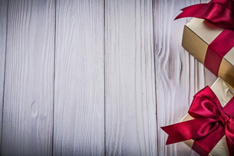 Gift boxes with tied red bows on wooden board copy space holiday concept