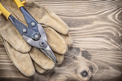 Pair of safety gloves steel cutter on vintage wooden board construction concept