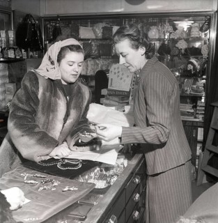 Shopping in the 1940s. A young woman in a store where a sales woman is presenting some of the