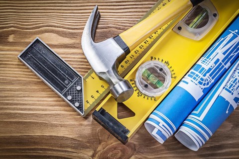 Blue engineering drawings construction level square ruler claw hammer on wooden board