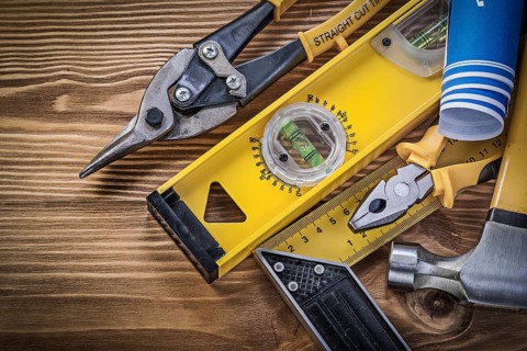 Blue blueprints construction level square ruler claw hammer pliers steel cutter on wooden board