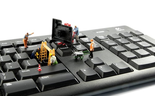 Little world figures repairing the key board of the computer or try to hack or intergate in the