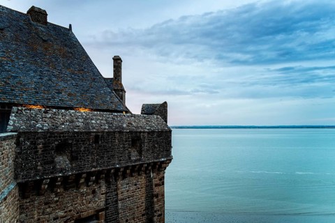 View of the ramparts of Mont Saint Michel with the tide coming in at sunset. Normandy, France,