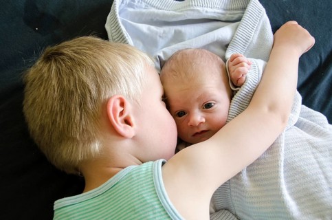 Baby with big eyes beeing cuddled by his older brother, Copenhagen, Denmark, Europe