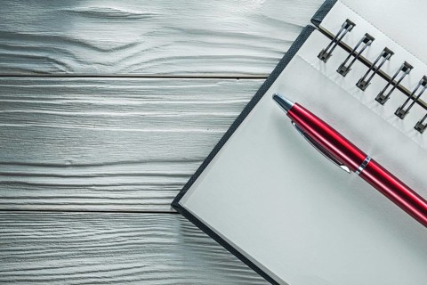 Opened notepad pen on white wooden board