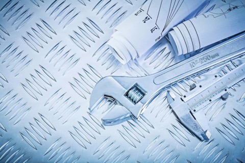Blueprints vernier caliper adjustable wrench on channeled metal sheet maintenance concept