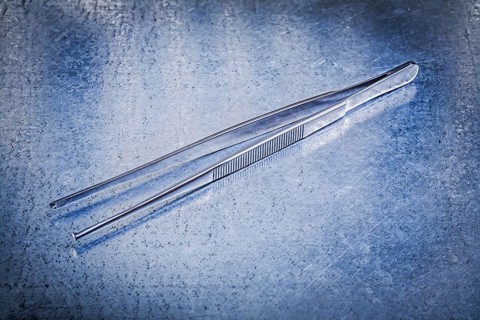 Pair of tweezers on metallic background medicine concept
