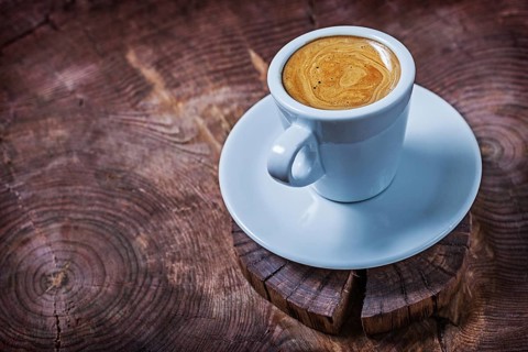 White coffee cup with capuchino on vintage wood cross cutted tree trunk