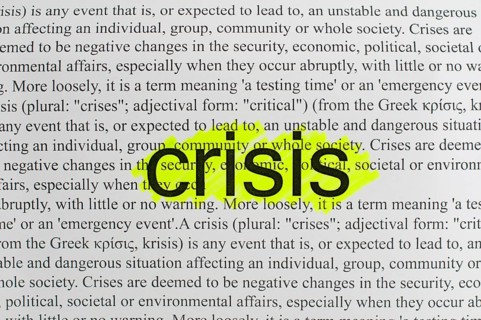 Typed text Crisis on white paper.Yellow marked