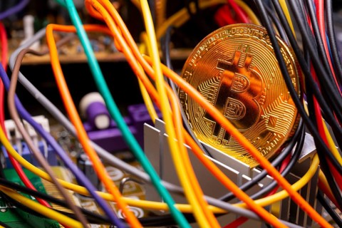 Virtual cryptocurrency money Bitcoin golden coin on a computer printed circuit board PCB surrounded