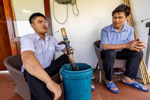 Two men on a terrace, one blowing out smoke, adding to the relaxed and casual atmosphere, Two men