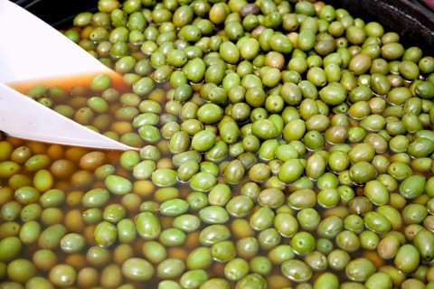 Brine green olive fruits in market round pot