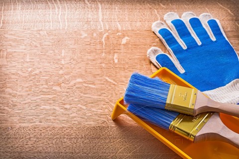 Wooden board with protective gloves paint tray and brushes construction concept