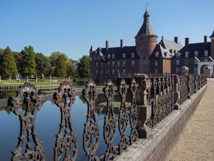Ornate iron fence along a moat with a view of a brick castle, anholt, isselburg, münsterland,