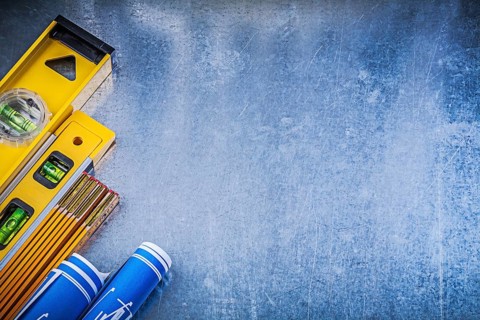 Blue blueprints levels yellow wooden meter on metallic surface