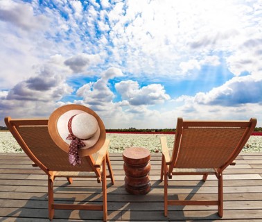 Comfortable sun loungers on a wooden platform. Delightful field of white bright spring
