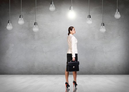 Business woman stands in a gray room with hanging bulbs