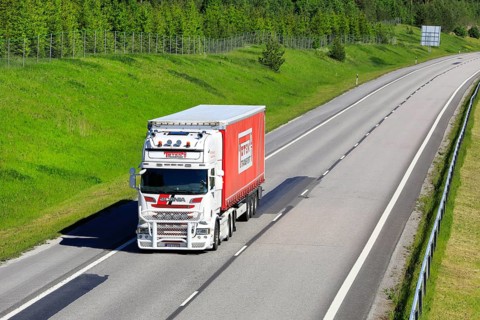 White and red Scania R560 semi trailer truck Toten Transport Oy transports goods along motorway