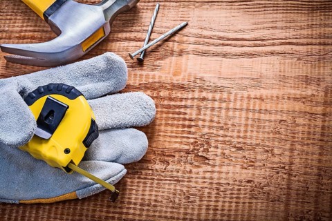Yellow roulette in protective glove hammer nails on vintage wooden board construction concept
