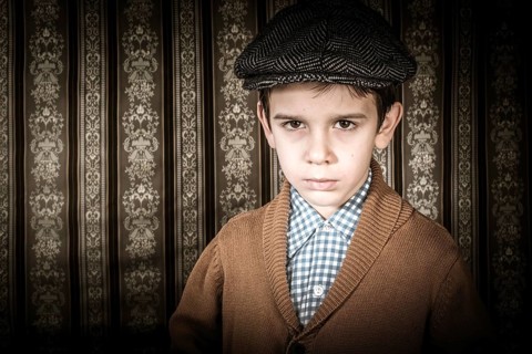 Frowning child in vintage clothes and hat. Close up shot